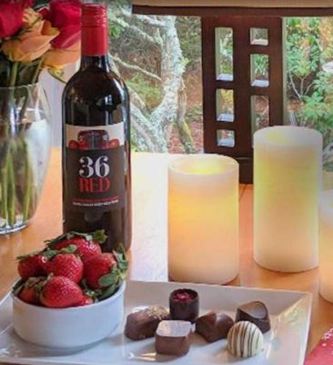 Wine, strawberries, chocolate candy, candles and flowers