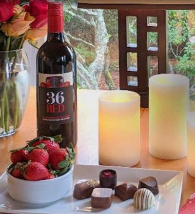Wine, strawberries, chocolate candy, candles and flowers