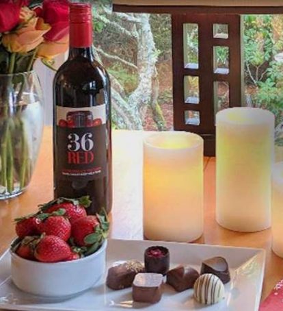Wine, strawberries, chocolate candy, candles and flowers