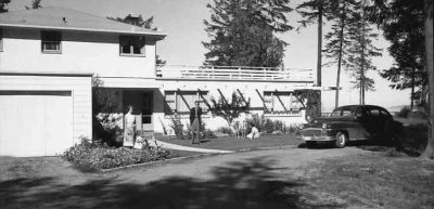 Historical view of home with older model car