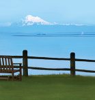 bench next to fence looking out over water and mountains in distance