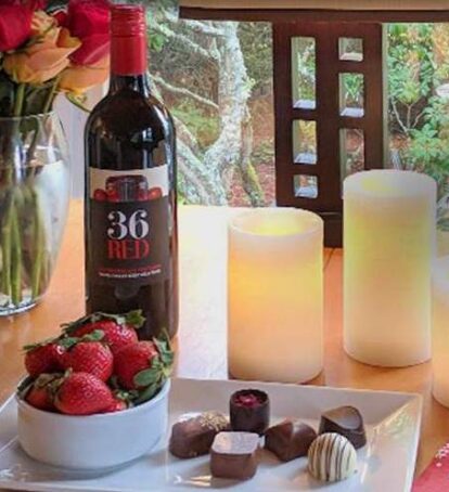 Wine, strawberries, chocolate candy, candles and flowers